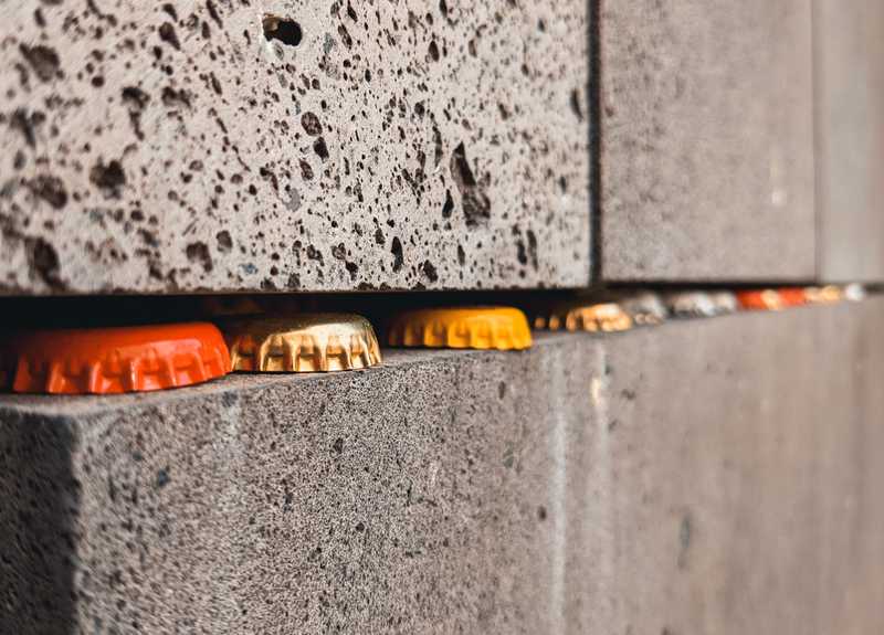 Orange, gold and yellow bottle caps wedged between two rough stone slabs.