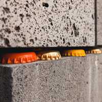 Orange, gold and yellow bottle caps wedged between two rough stone slabs.